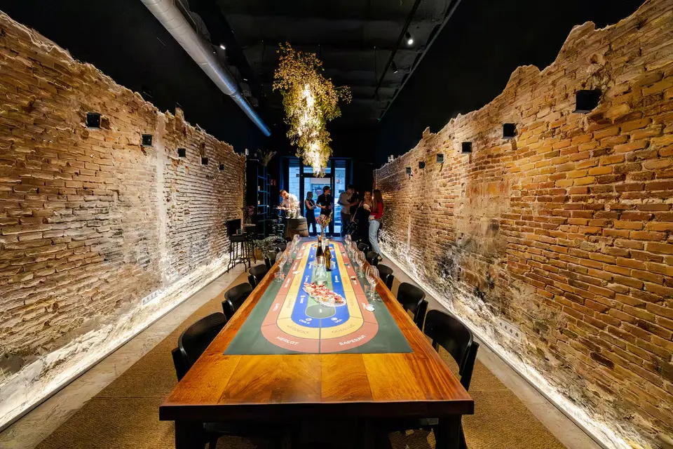 Long wooden table with a track-shaped game board between two exposed brick walls lit from below