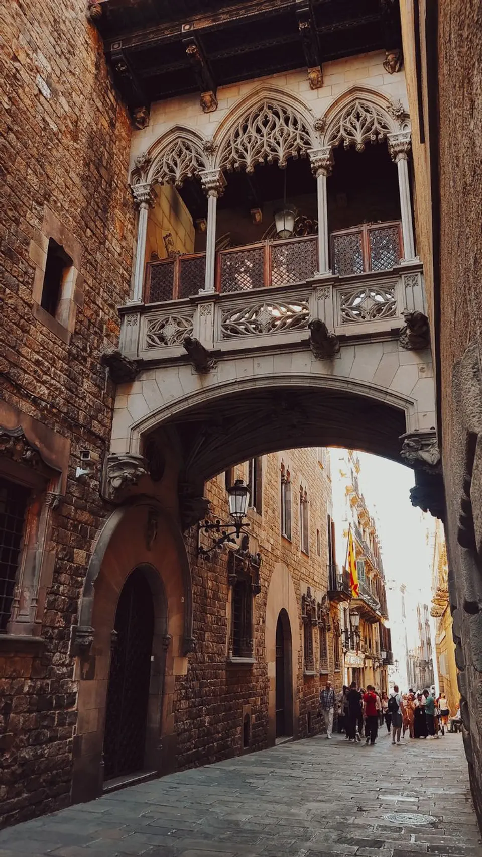 Gothic-style covered bridge with a tracery balcony over a narrow street between stone buildings