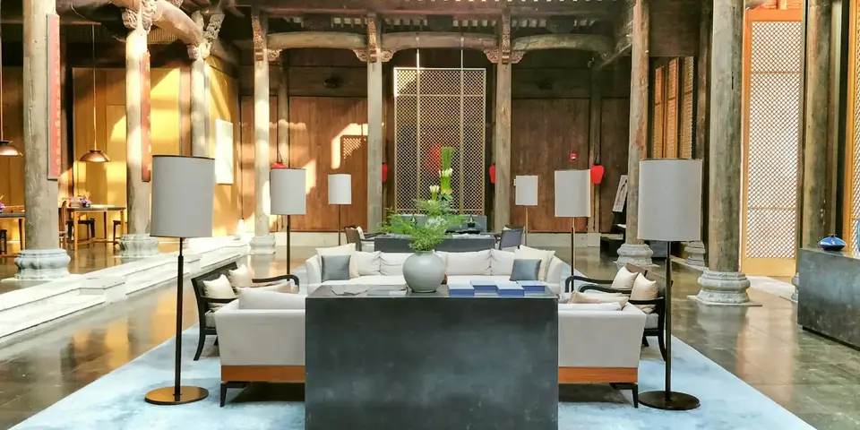 Hotel lounge with white sofas, floor lamps and wooden columns