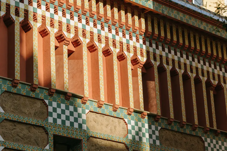Façade detail with reddish brackets, green and white tile bands and stone panels